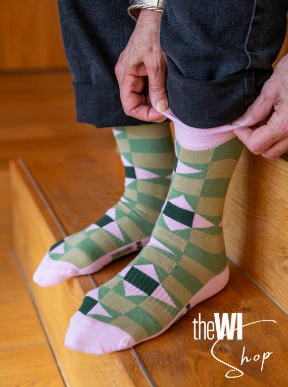 Person sitting on the edge of a bed pulling up their socks with their hands.