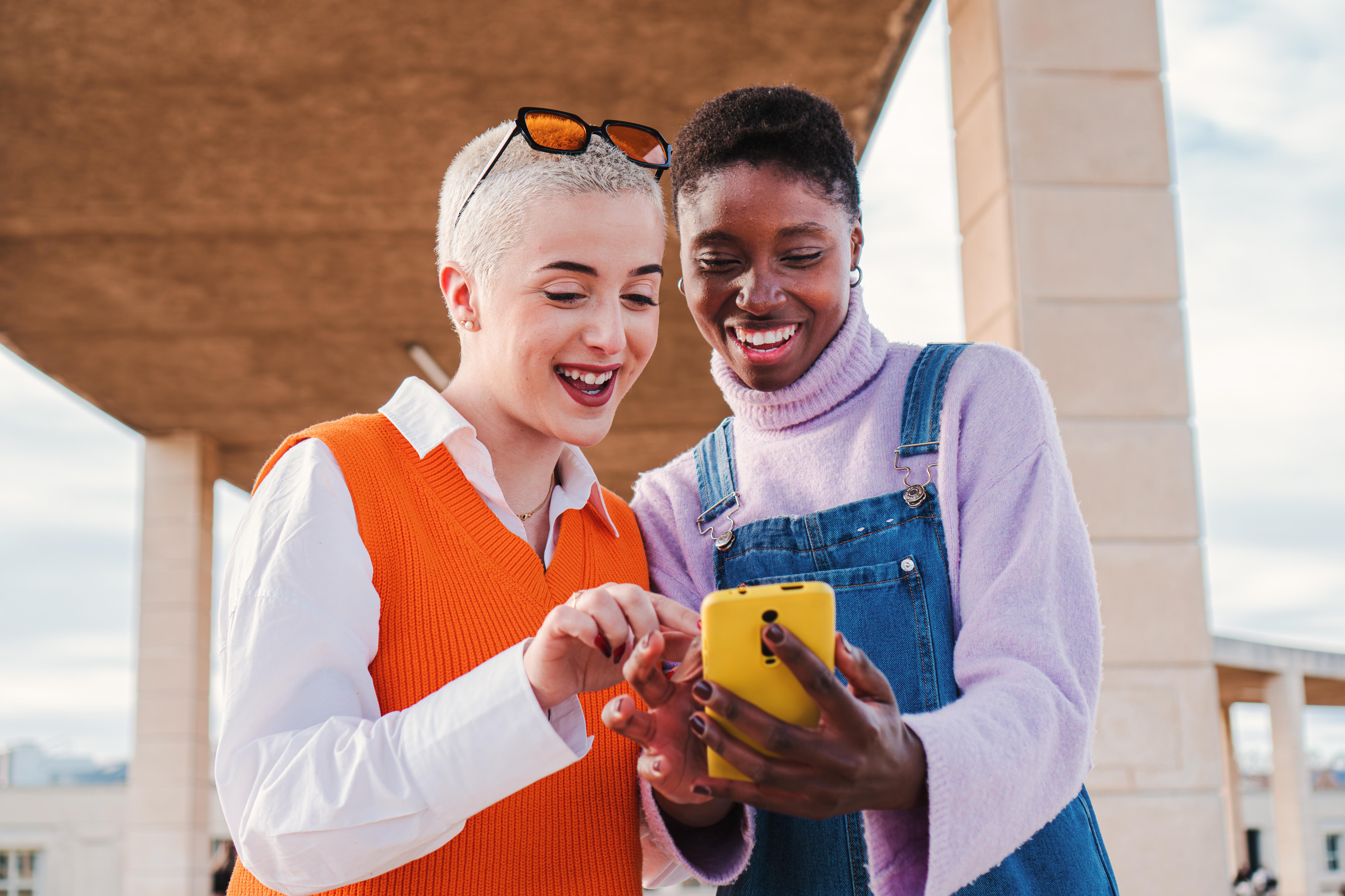 Two women smiling looking at a smart phone
