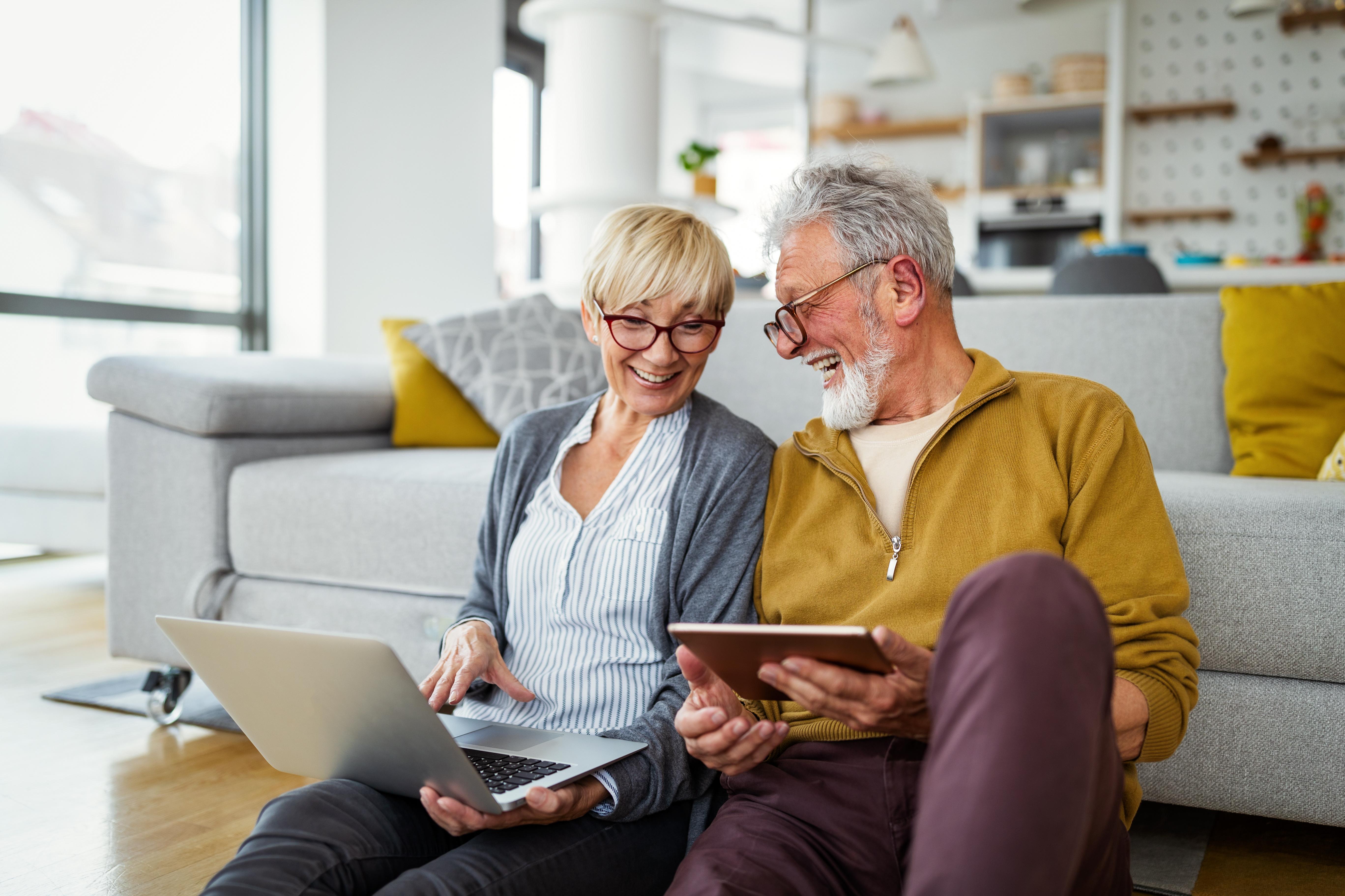 A couple laughing together holding a digital tablet