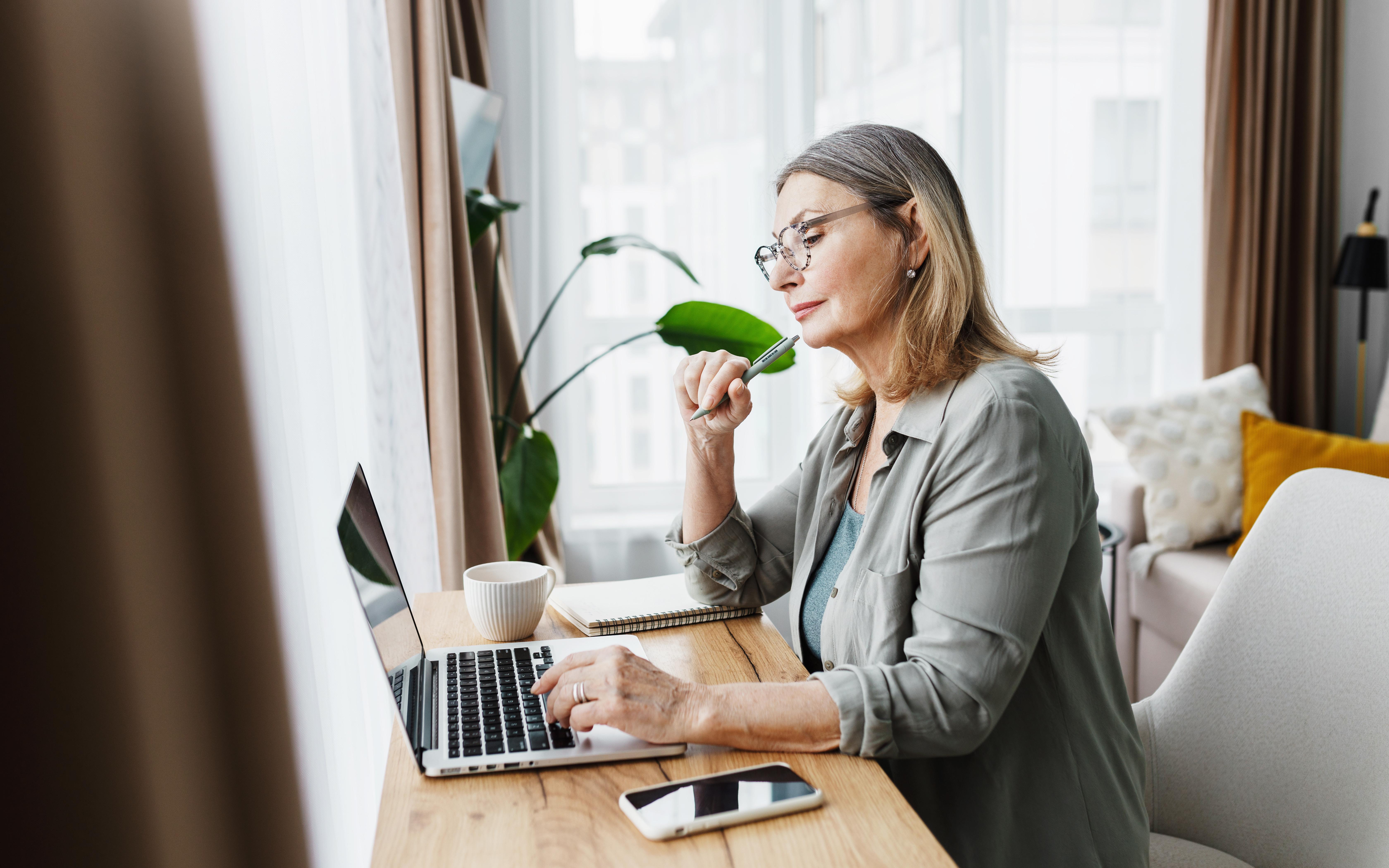 Woman sat at laptop taking notes