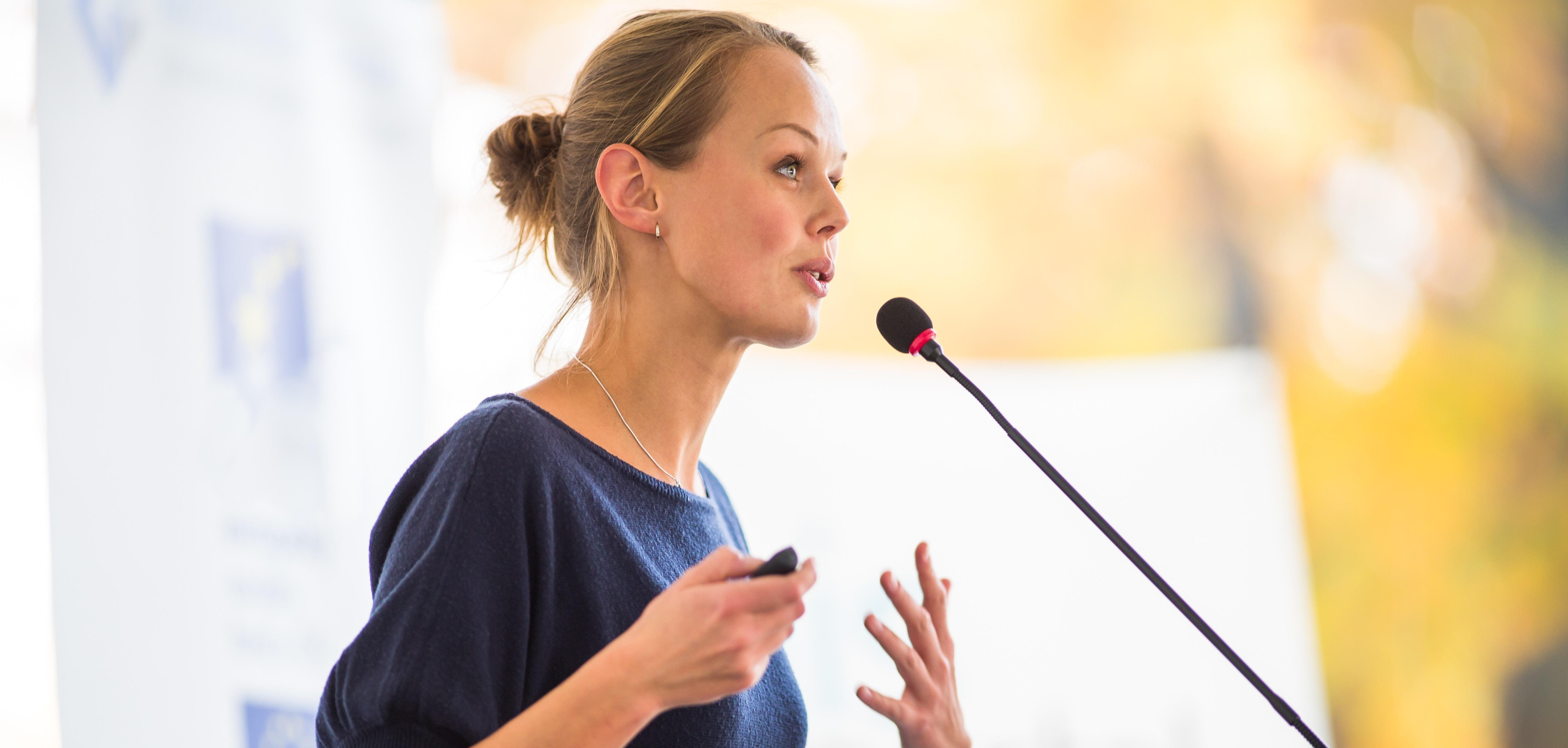 woman speaking into a microphone giving a speech